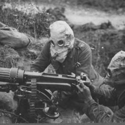 Machine gunners in action wearing gas helmets