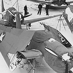 U.S. Navy aircraft carrier at a North Atalantic port. Spotted on the snow-covered flight deck are Douglas DAUNTLESS dive bombers and Grumman AVENGER torpedo planes
