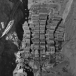 Dam structure as seen from skip on 150-ton cableway. View is made on center line of structure from elevation 1000. Construction railroad trestle seen against Nevada canyon wall. View looks upstream