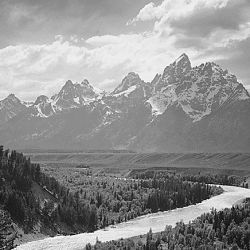 View from river valley towards snow covered mountains, river in foreground from left to right, "Grand Teton" National Park, Wyoming.