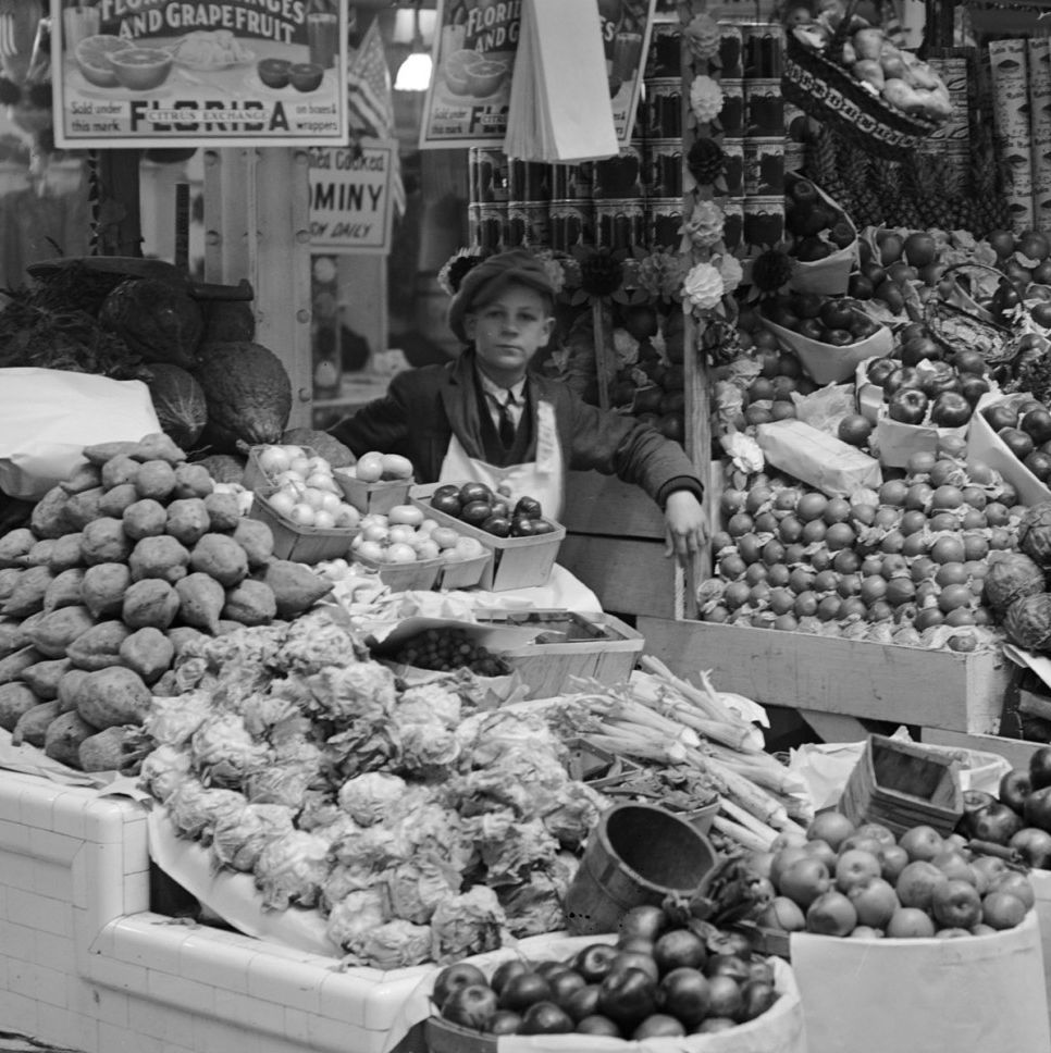 Young boy tending freshly stocked fruit and vegetable stand at Center Market
