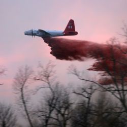 [Severe Wildfire Threat] Ratliff, OK, January 18, 2006 -- A Lockheed P2 V5 "Neptune" airplane drops its load of 2080 gallons of fire retardant just before air operations are ceased due to darkness. Si