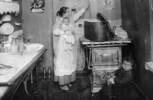 Woman Holding a Baby while Doing Laundry