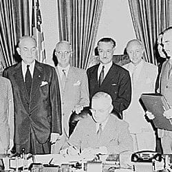 Photograph of President Truman signing the document implementing the ...